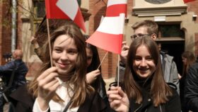 Uczennice pozdrawiające uczestników Defilady machają flagami Polski.