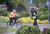 Policjant z uczestnikiem jadącym na rowerze.