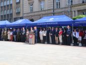 Goście podczas uroczystości na placu, stojący pod niebieskim namiotem z napisem Wojewoda Małopolski