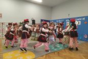 Dzieci w krakowskich strojach tańczą regionalny taniec.