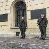 Żołnierze w pełnym umundurowaniu stojący na baczność podczas służby z bronią na ramieniu