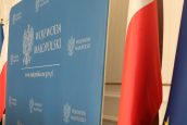 Rollup Wojewody Małopolskiego oraz flagi Polski oraz Unii Europejskiej umieszczone w Sali