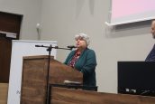 Małopolska Kurator Oświaty dr Gabriela Olszowska mówiąca ze sceny do zgromadzonych osób, gratulując im wzięcia udziału w wydarzeniu.