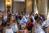 Widok publiczności zgromadzonej w sali, gdzie odbywała się uroczystość. Widzowie z zaciekawieniem słuchają wykładu