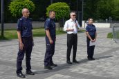 Małopolski Wicekurator Oświaty oraz przedstawiciele Policji stoją w rzędzie w trakcie rozpoczęcia wydarzenia, Wicekurator mówi do mikrofonu.