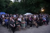 Zaproszeni goście na wydarzenie Święta Francji, siedzą na przygotowanych krzesłach i obserwują jedno w występów artystycznych.