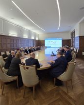 Widok ogólny sali, gdzie odbywała się narada. Za stołem widoczna jest wyświetlona prezentacja. Przy stole siedzą Kuratorzy.