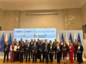 Grono honorowych Profesorów Oświaty stojących wraz z Minister Edukacji. 26 osób stojących na stenie w galowych strojach trzymających w rękach odznaczenia.