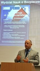 Wojewoda Małopolski dr. Krzysztof Jan Klęczar w trakcie wystąpienia. Z tyłu wyświetlany plakat z programem konferencji.