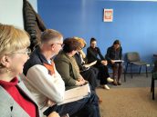 Uczestnicy spotkania siedzący na krzesłach pod ścianą.