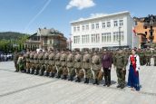 II Małopolska Wicekurator Oświaty wraz z klasami wojskowymi w jednym rzędzie w trakcie uroczystości. Za nimi powiewają flagi, wydarzenie obserwują także rodzice.