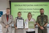 Wicekurator Artur Pasek oraz przedstawiciele ZHP z osobą wyróżnioną. W tle slajd z napisem Szkoła Przyjazna Harcerstwu.